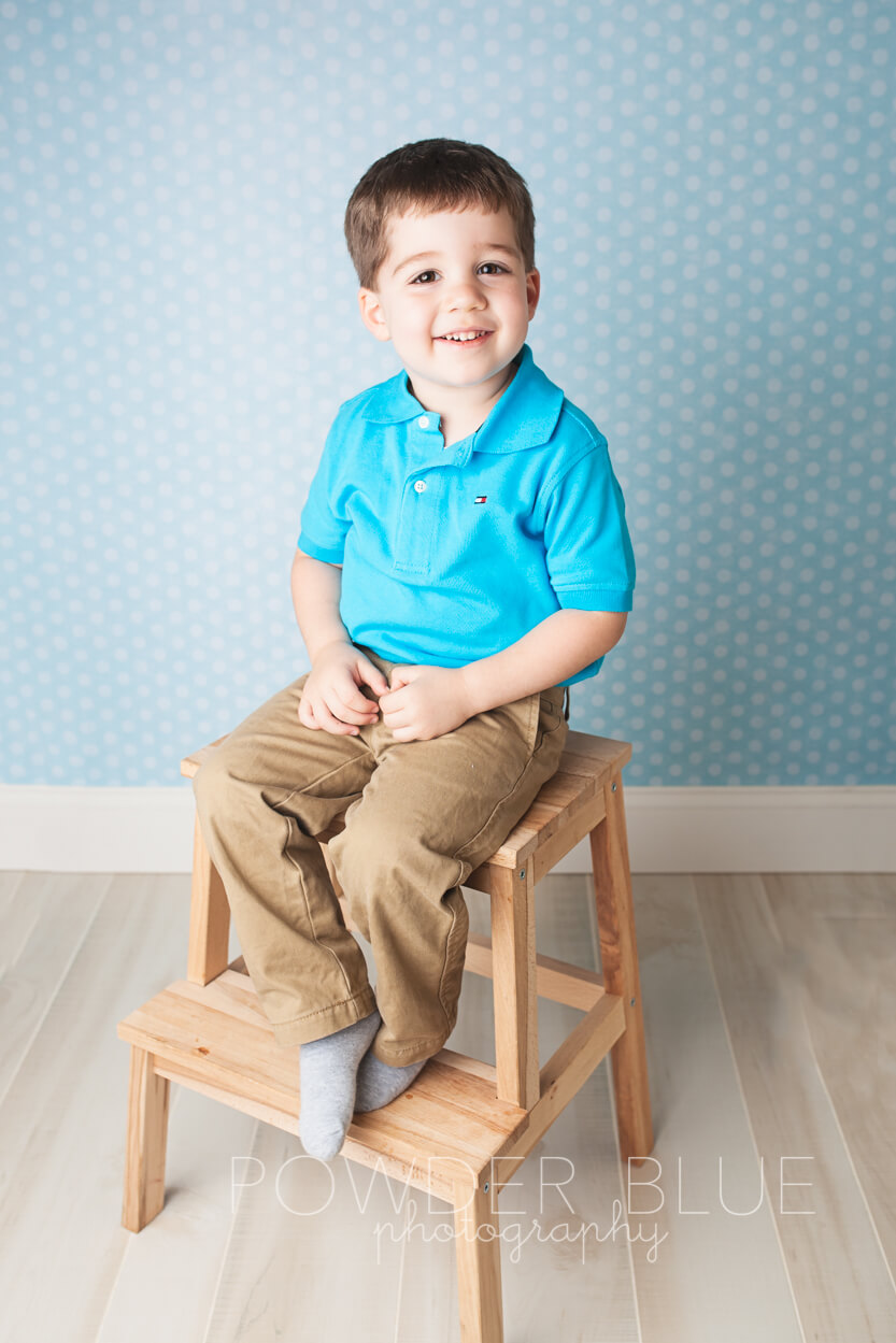 2 1/2 year old boy laughing sitting on a stool