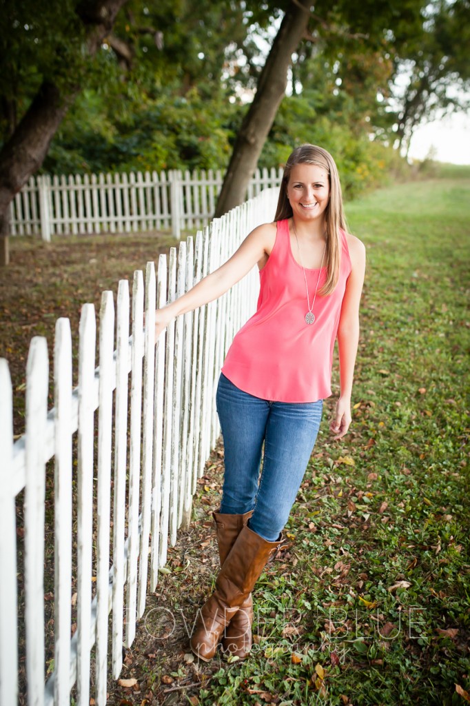 senior girl standing in a field pittsburgh by cemetery fence pink shirt boots