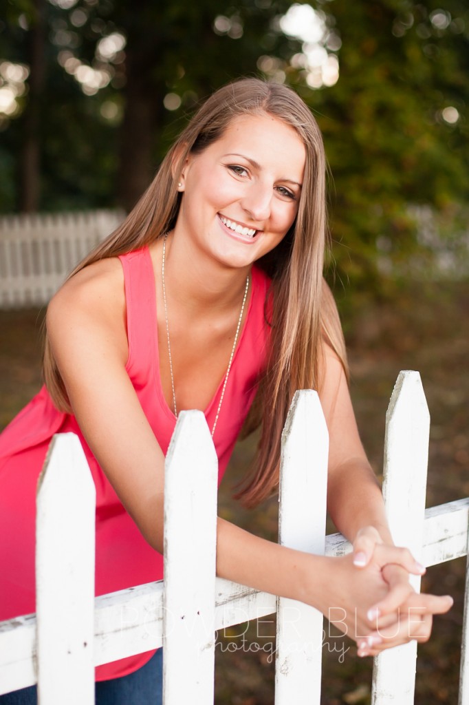 senior girl standing in a field pittsburgh by cemetery fence pink shirt boots