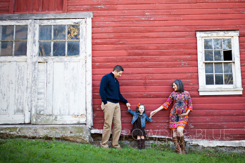 upper st clair portrait photographer, family holding hands in front of a red barn in pittsburgh, 2 year old toddler with mom & dad.