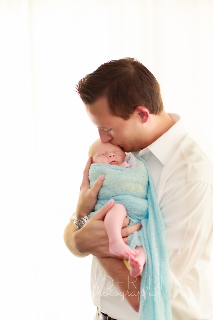 dad kissing newborn baby boy 4 weeks old