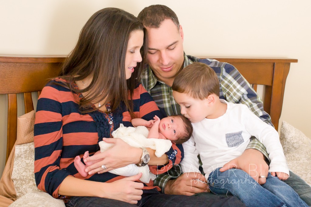 family looking at newborn baby boy on a  bed