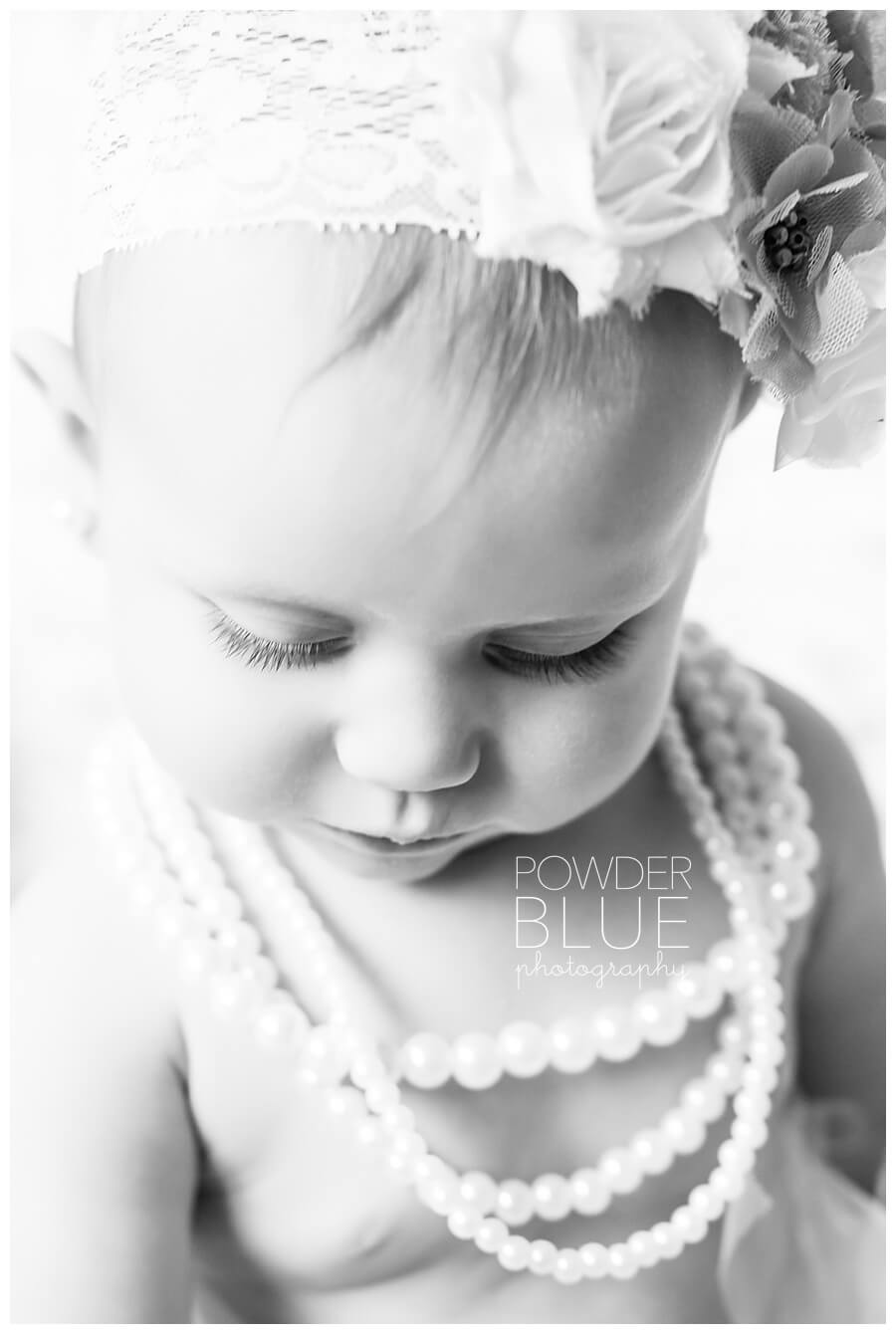 9 month old baby girl studio portrait with cream flokati run and eggnog seamless backdrop pearls