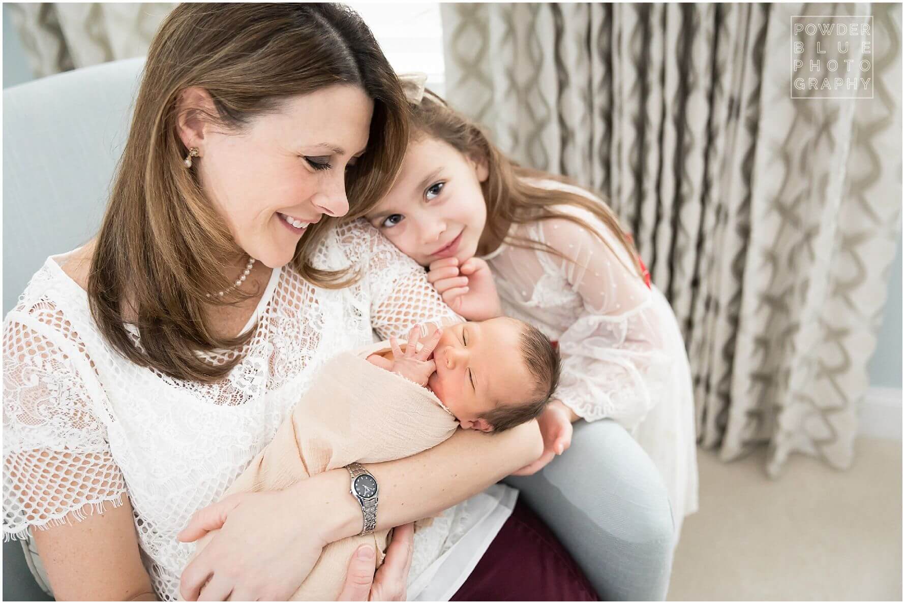 girl leaning on mom's shoulder with newborn baby boy.