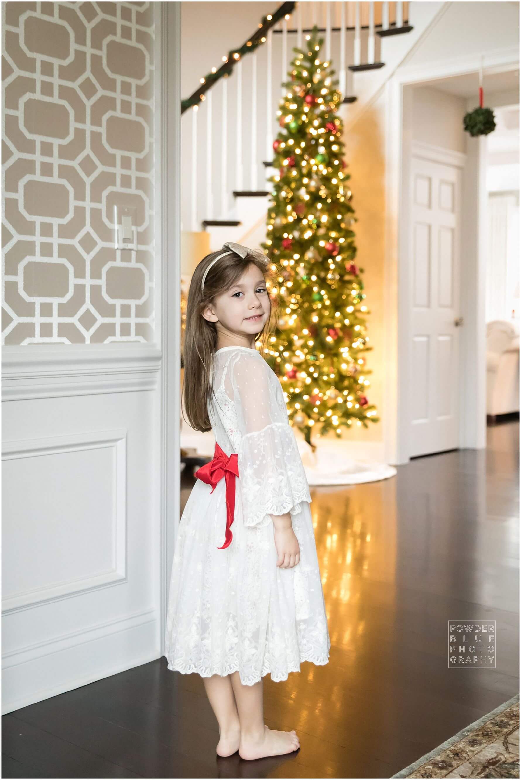 little girl in front of christmas tree with chasing fireflies dress.
