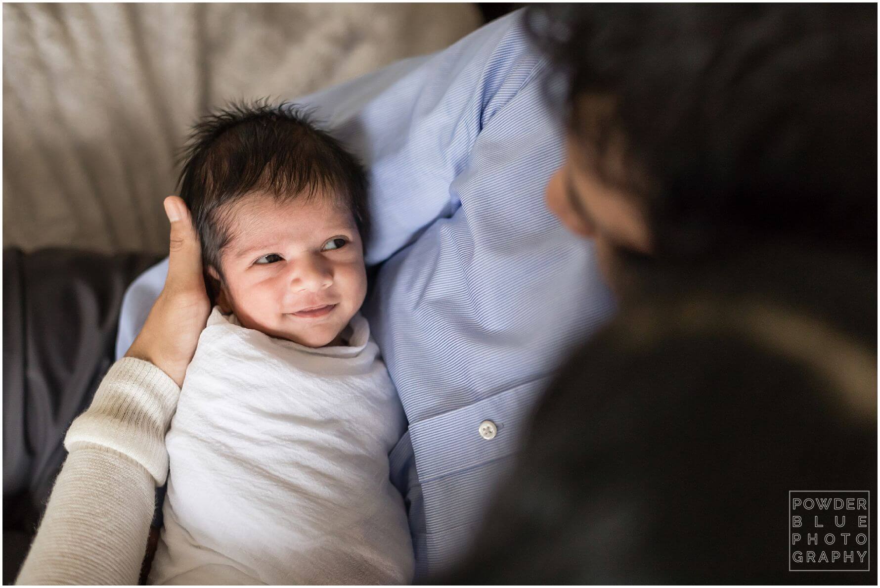 smiling newborn baby. pittsburgh newborn photographer lifestyle photography session. newborn baby in black & white and color portraits on a bed in a home.